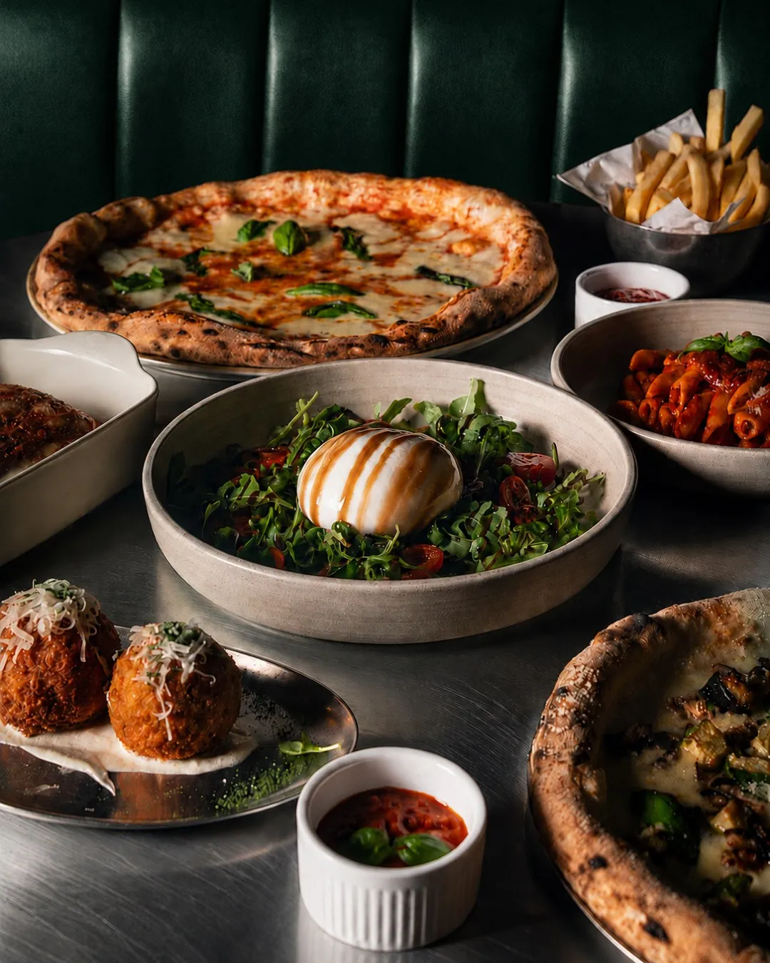 A shared table of pizza, salads and small plates